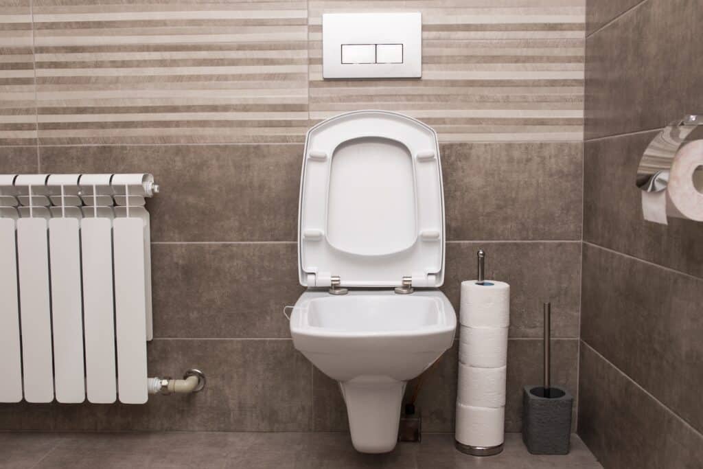 New white ceramic toilet on a gray tile background.
